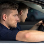 Company Strike Focused driver behind the wheel of a vehicle with a passenger seated beside him